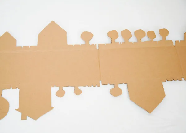 A cardboard road made from a box is a fun DIY toy for kids. Cut out trees and houses on the outer edges and paint them in vibrant colors. | at Non Toy Gifts
