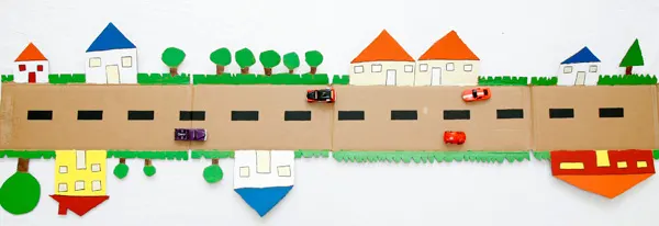 A cardboard road made from a box is a fun DIY toy for kids. Cut out trees and houses on the outer edges and paint them in vibrant colors. | at Non Toy Gifts