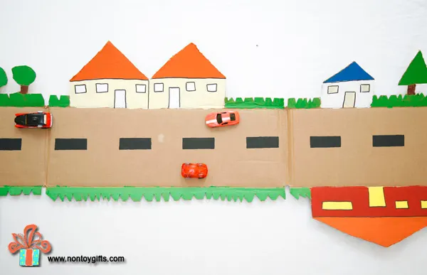 A cardboard road made from a box is a fun DIY toy for kids. Cut out trees and houses on the outer edges and paint them in vibrant colors. | at Non Toy Gifts