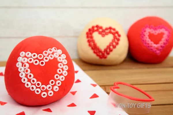 These play dough Valentines make great Valentine non-candy treats for preschool and kindergartner classroom party. Fun Valentine's Day activity for kids. Use heart shaped cookie cutter and decorate with beads | at Non-Toy Gifts