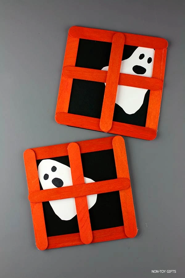 Simple Halloween popsicle stick craft where children create a ghost looking through a handmade orange window frame for classroom or home fun