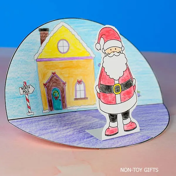 Santa standing in front of a Christmas house diorama craft