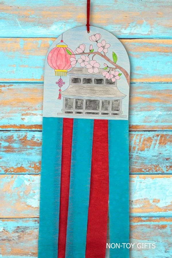 Chinese New Year decoration craft printable for kids featuring a pagoda, lantern, cherry blossoms, and hanging paper streamers.